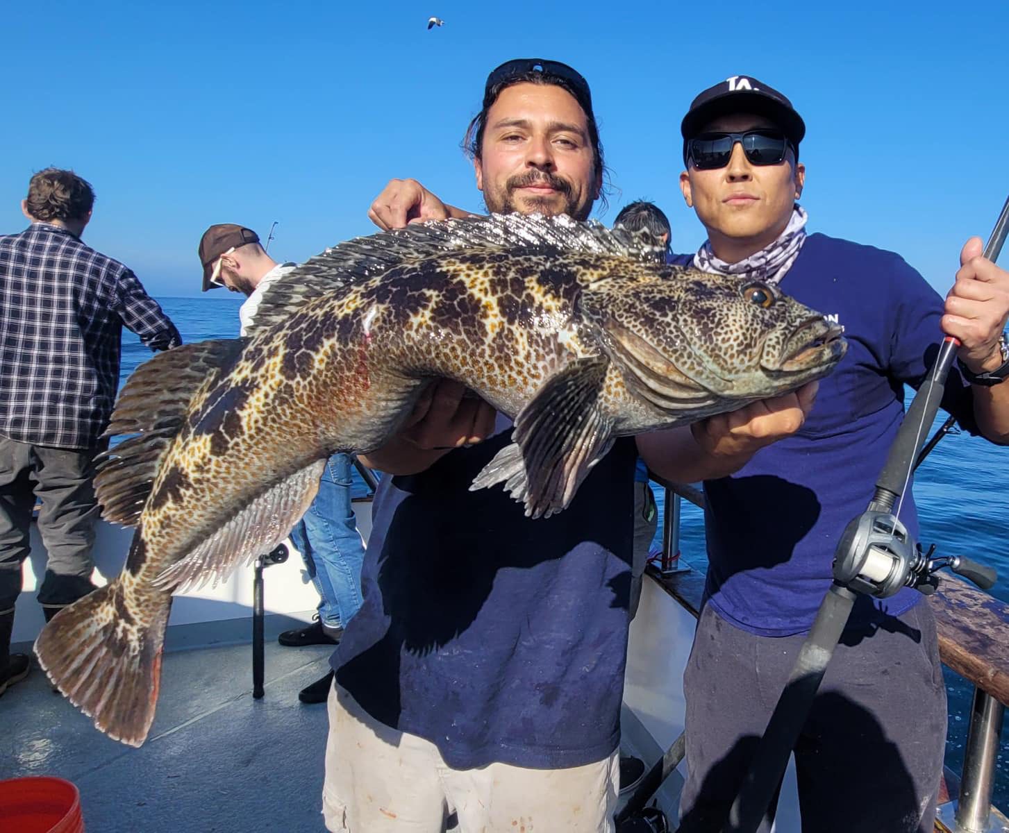 Friends showcasing a big fish on a boat.