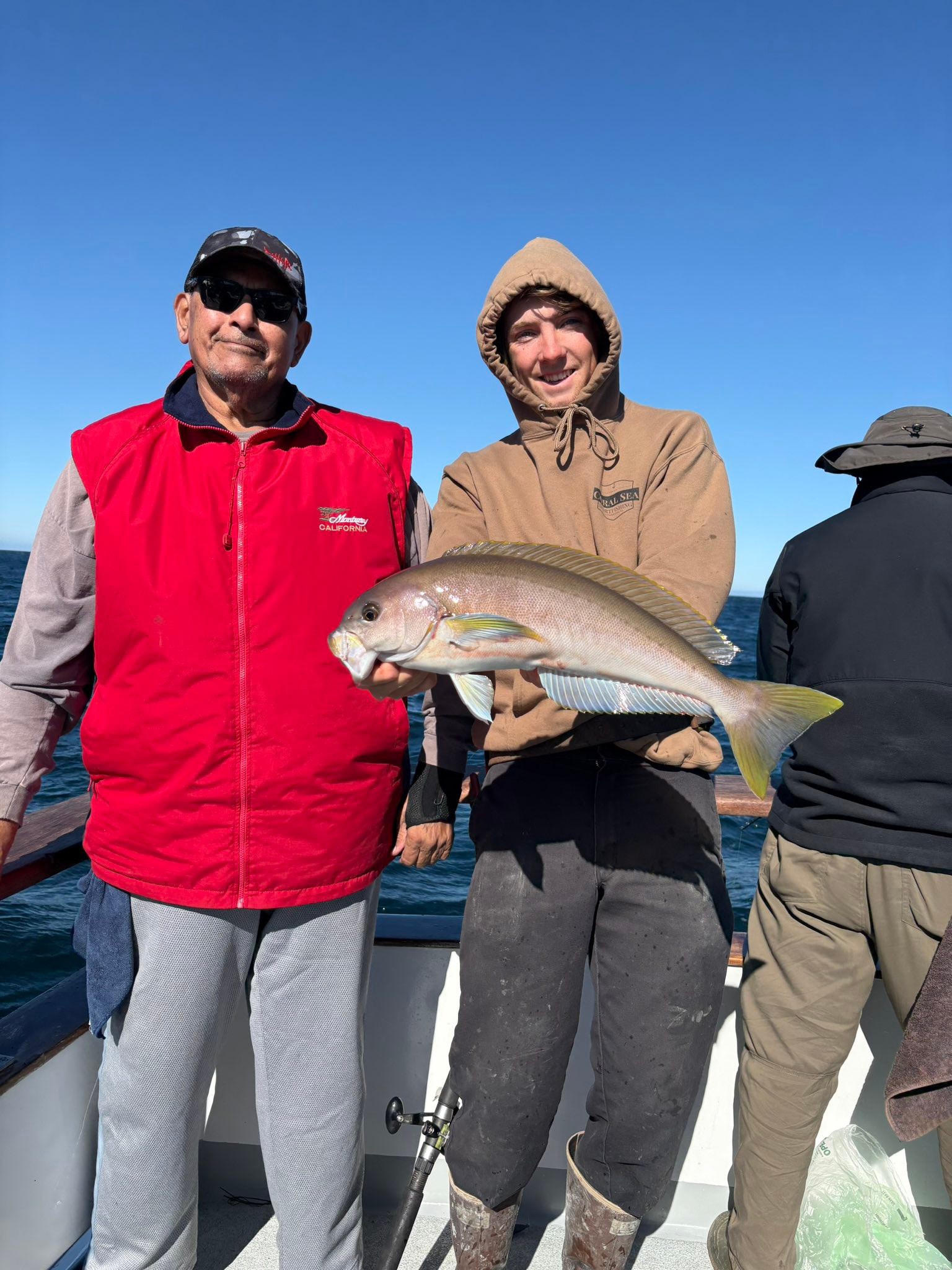 Man holding fish on boat with companions