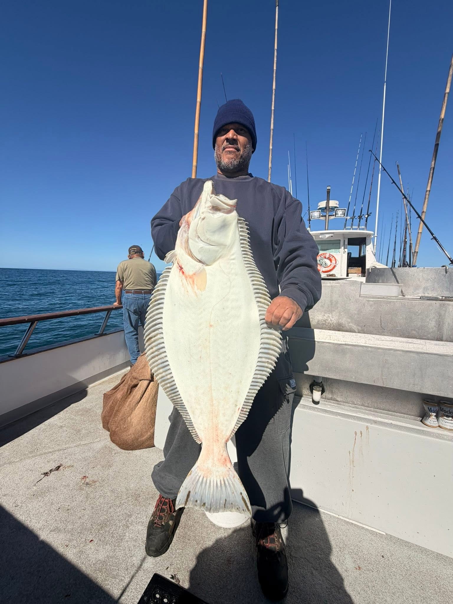 Fisherman holding large flatfish on boat