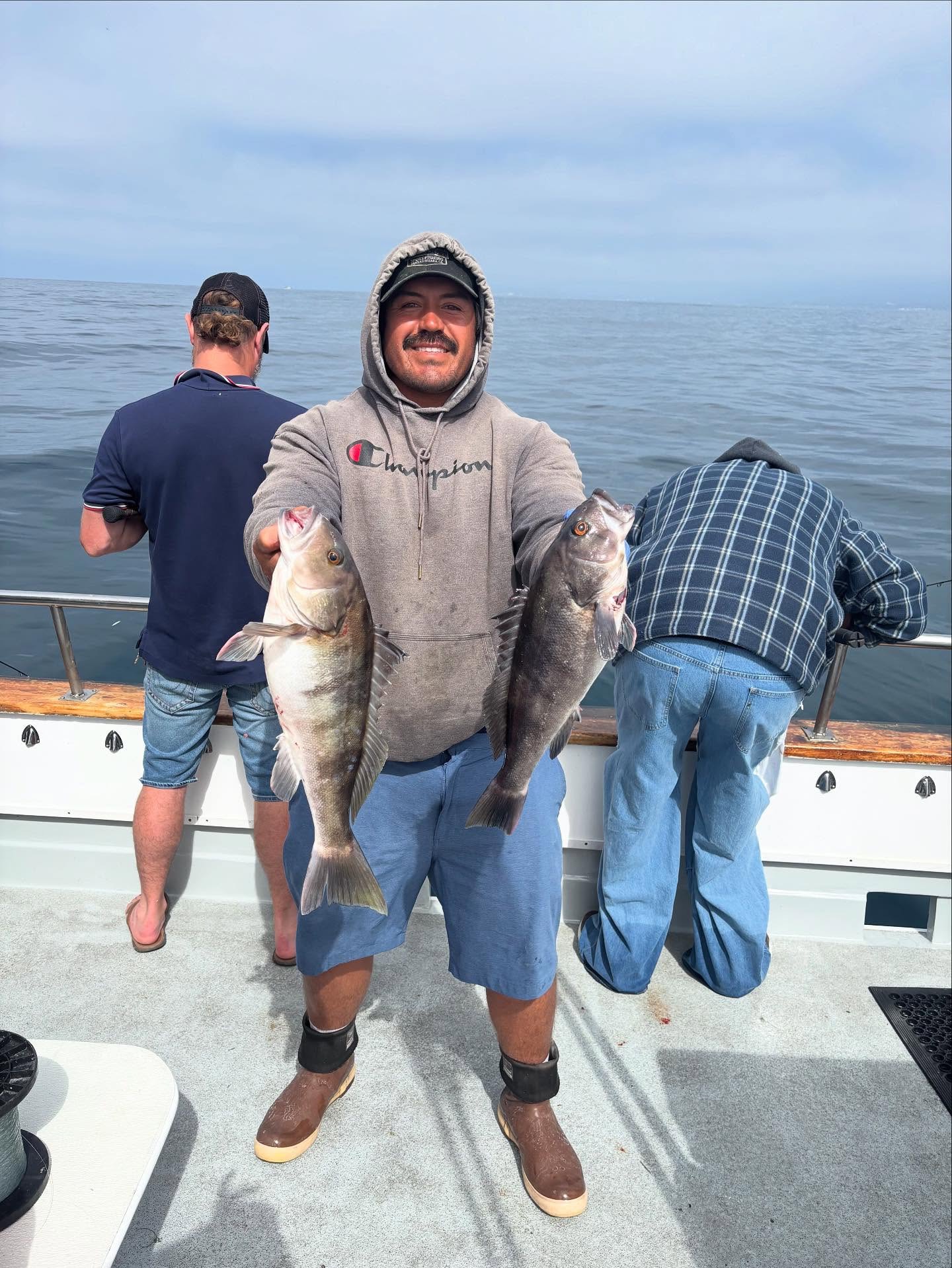 Smiling fisherman holding two fish on boat