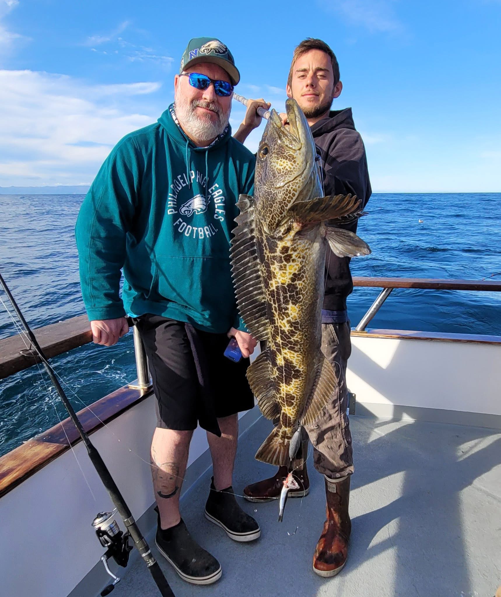 Two anglers holding large fish on boat