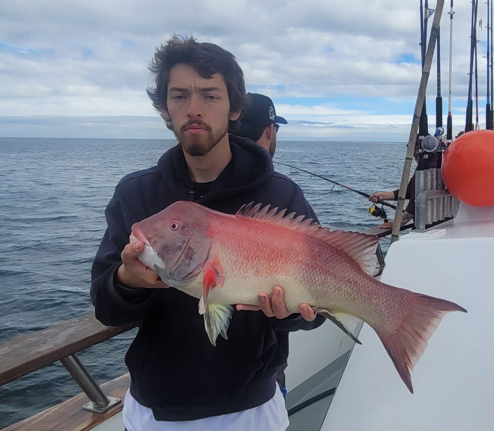 Man holding large pink fish on boat