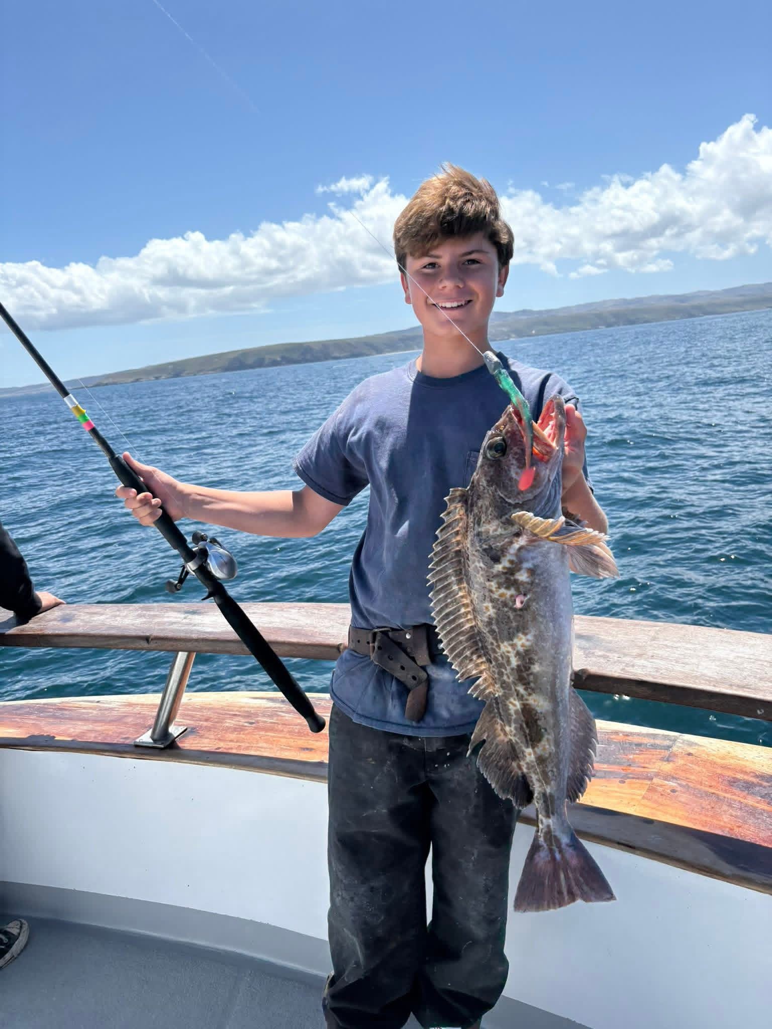 Young man holding large fish on boat