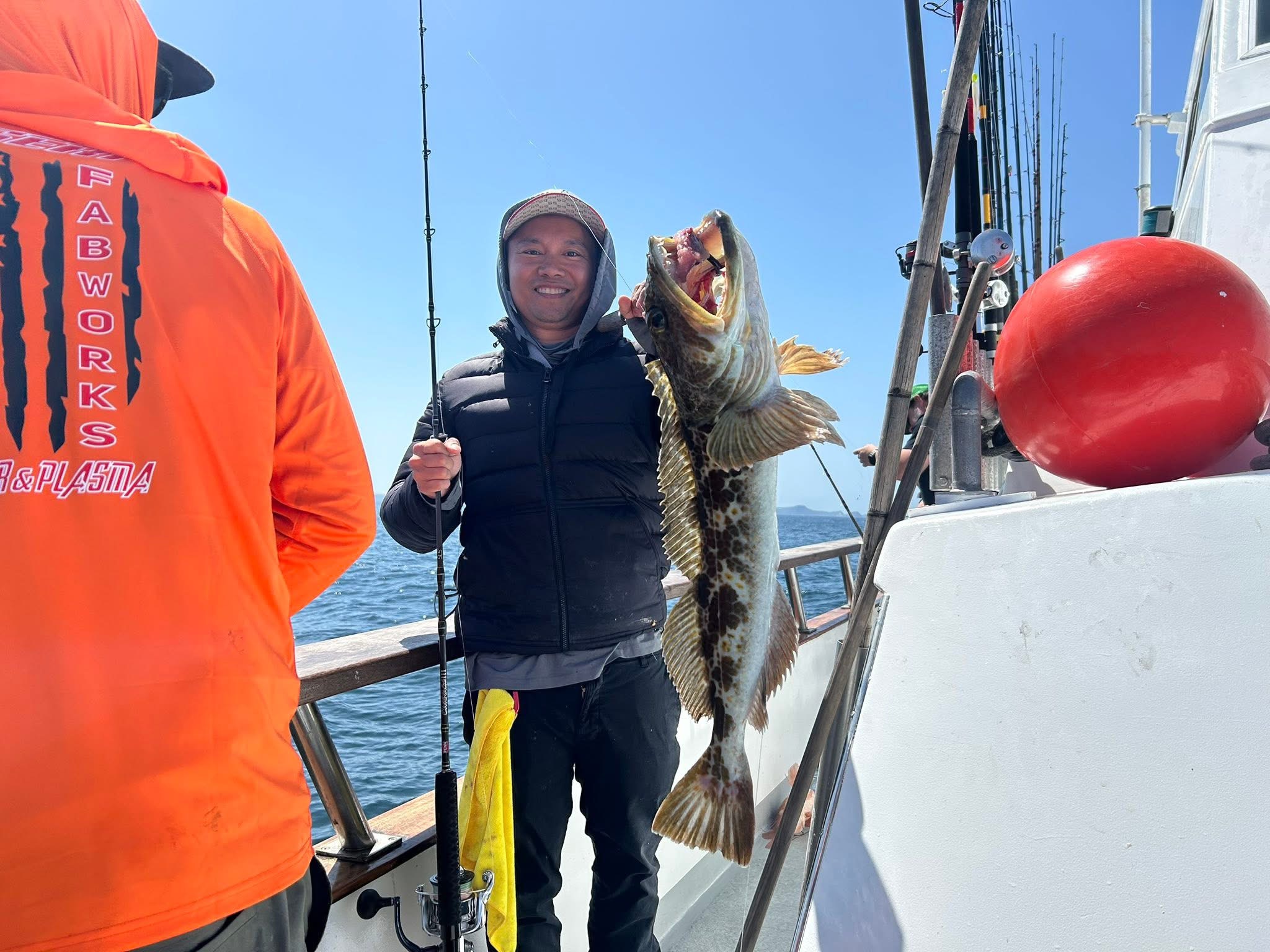 Smiling angler holding large fish aboard boat