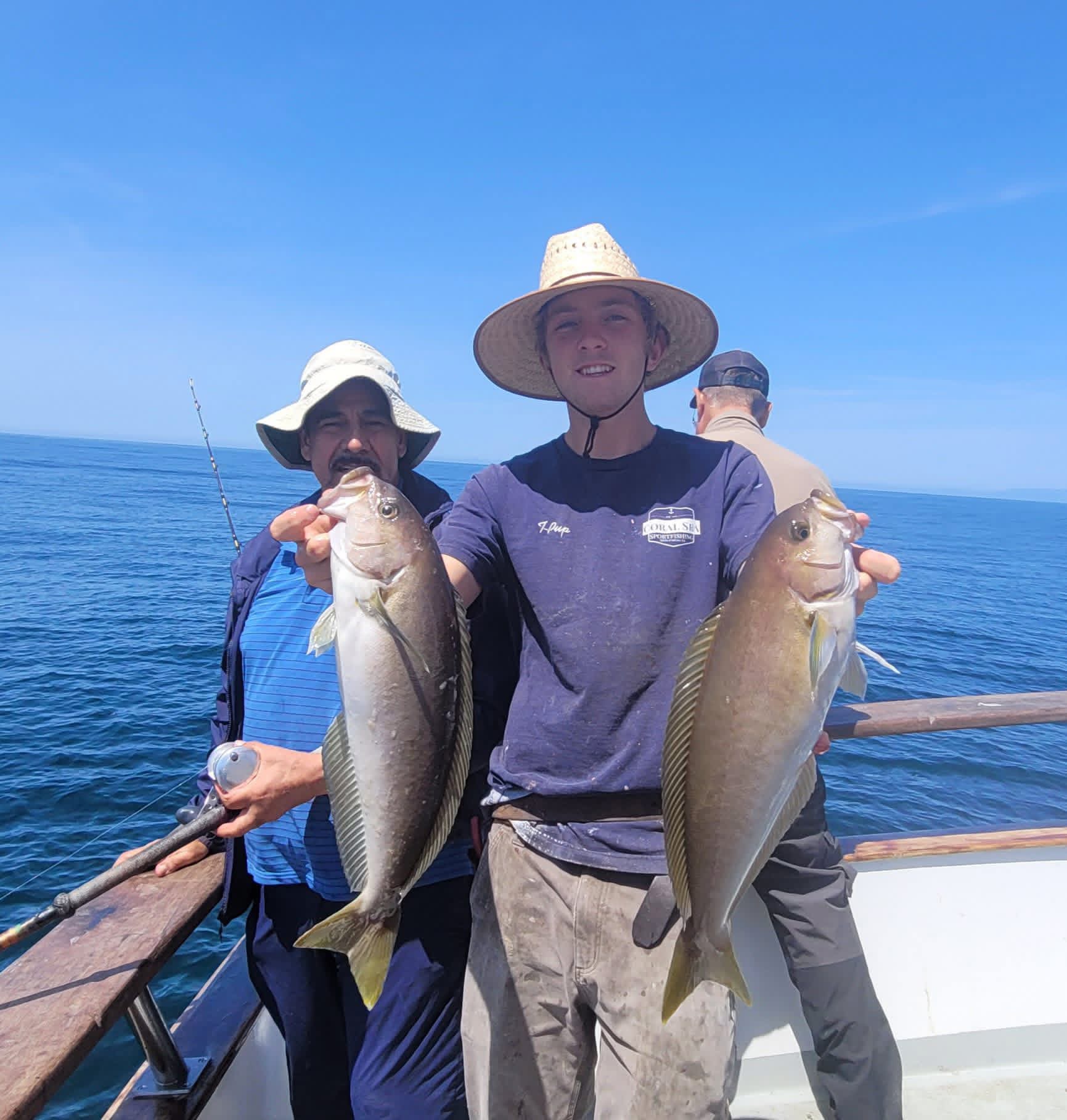 Fishermen on boat holding two large fish