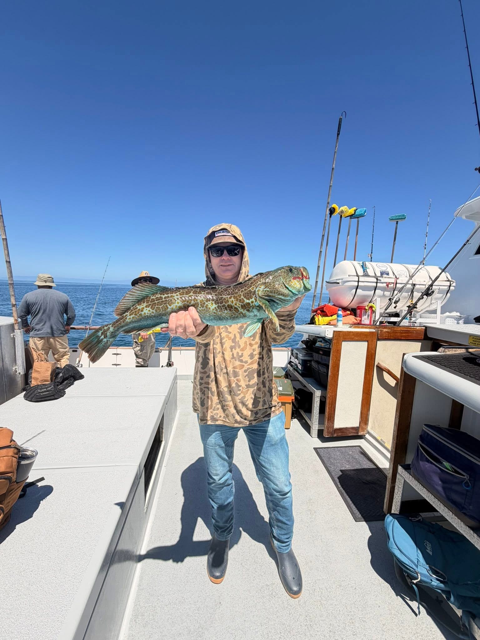 Person holding large green fish on boat