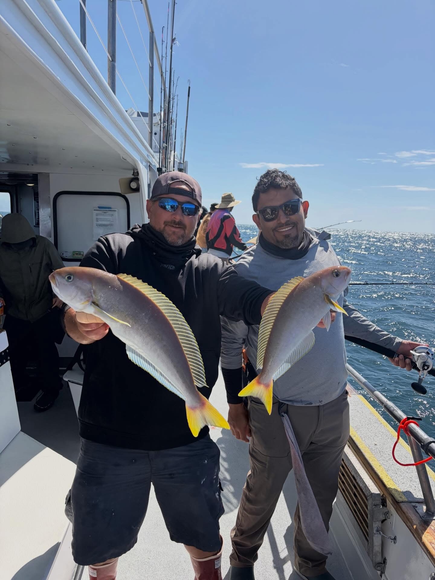 Two men holding fish on fishing boat