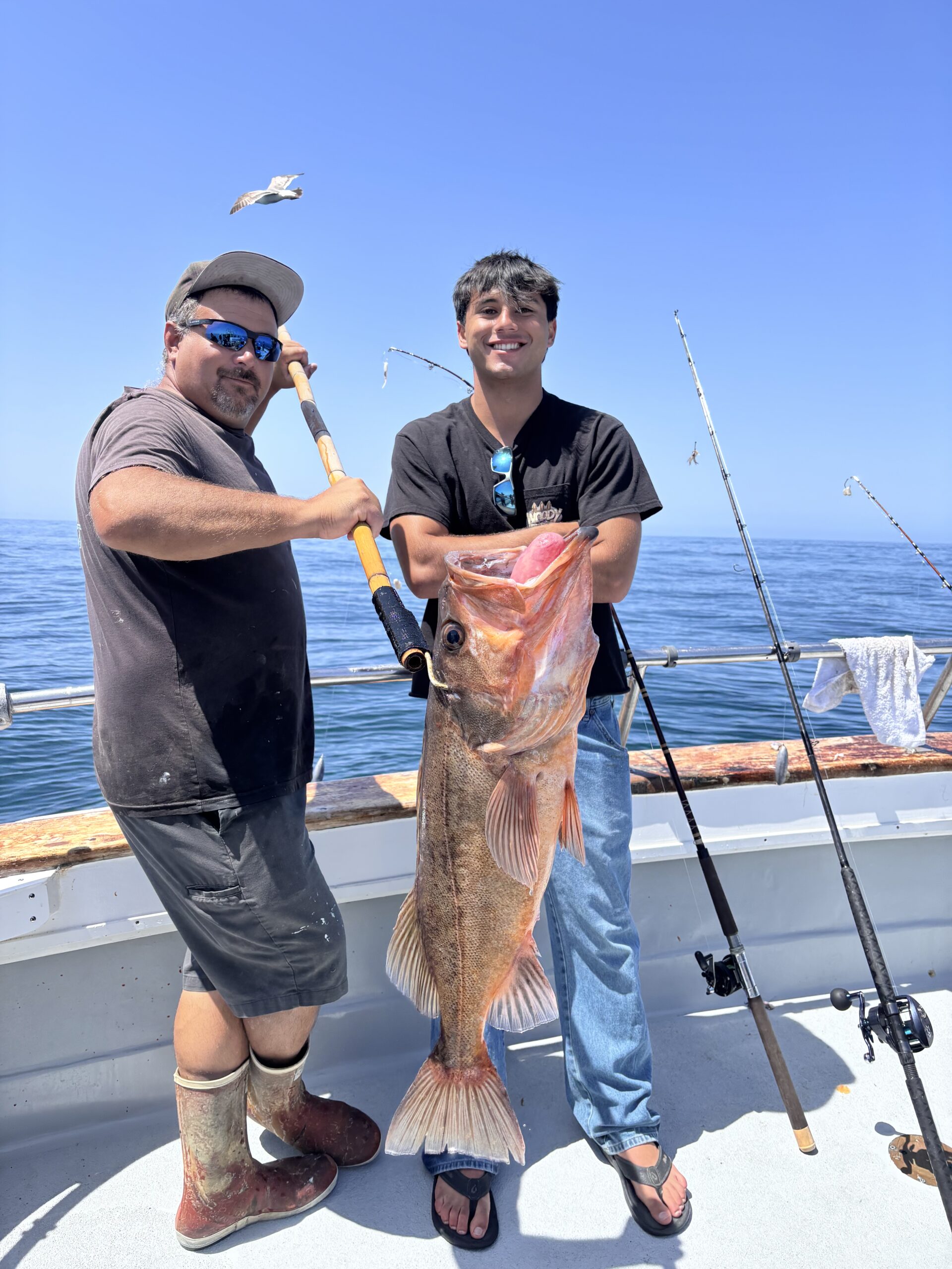 Two fishermen holding large caught fish