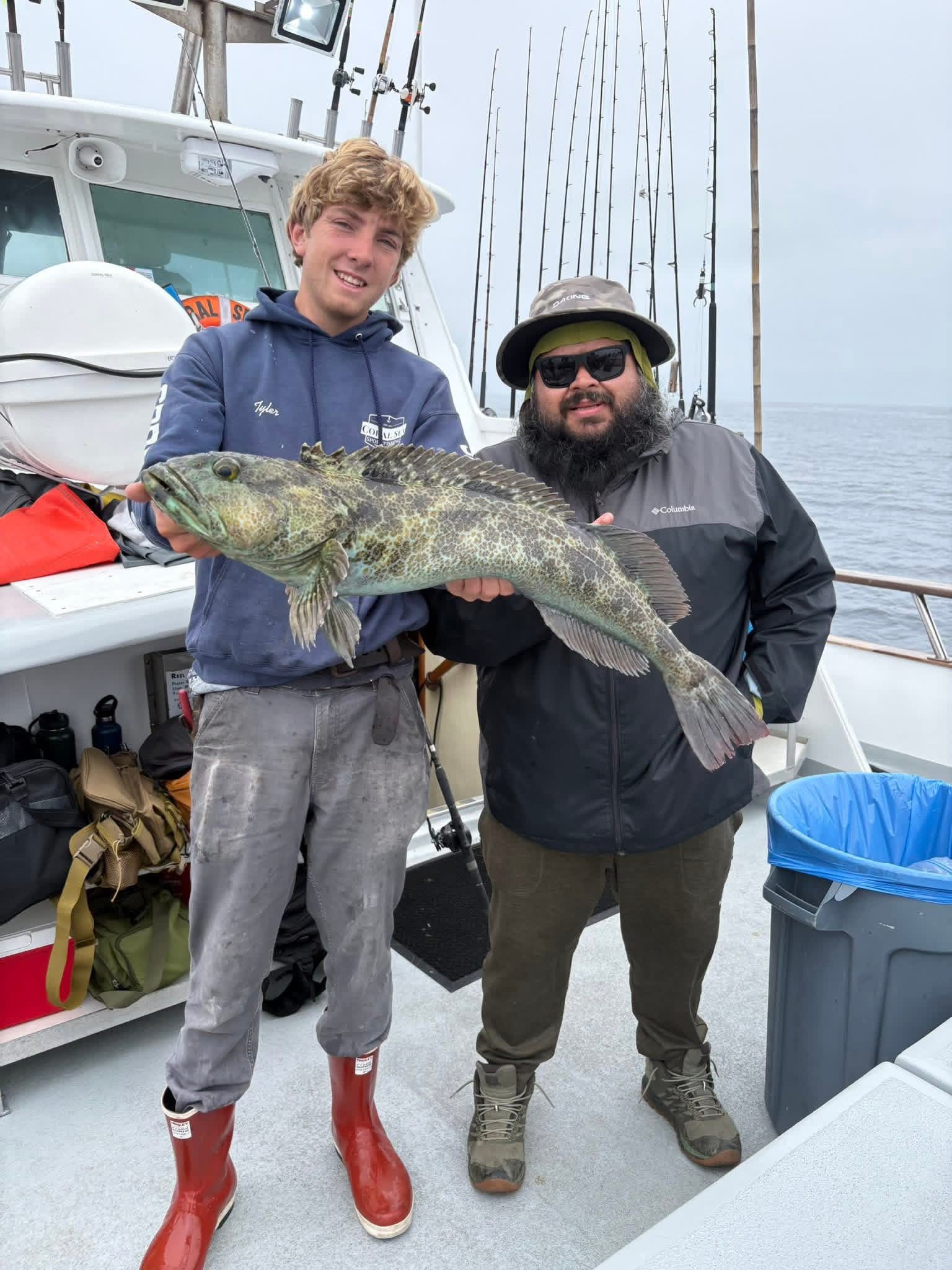 Two fishermen on boat holding large fish