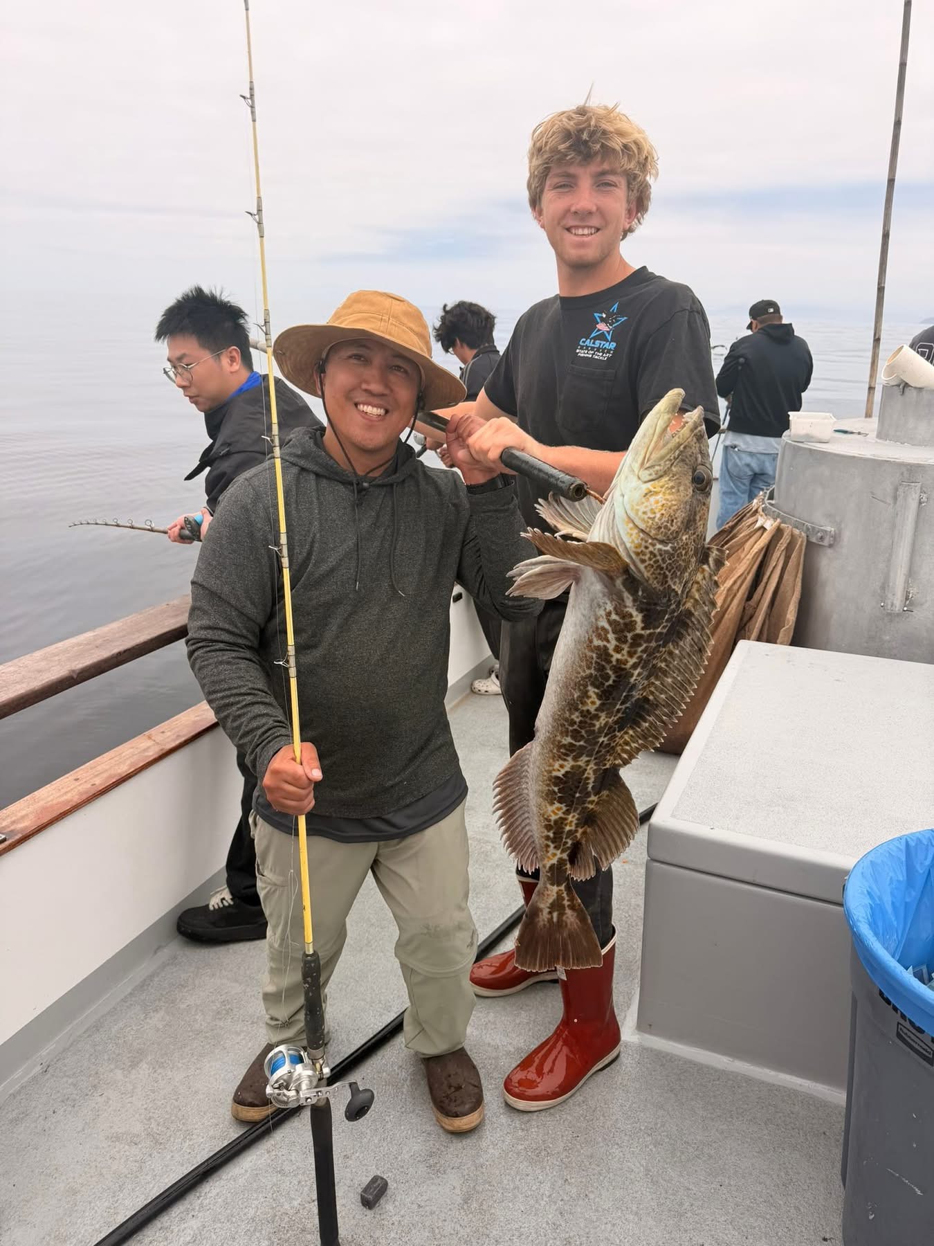 Anglers smiling on boat holding large fish
