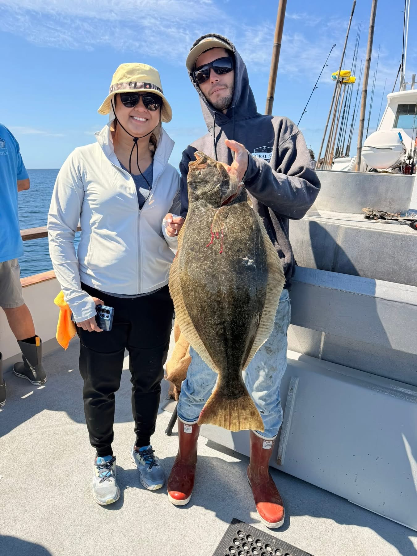 Two anglers holding large halibut on boat
