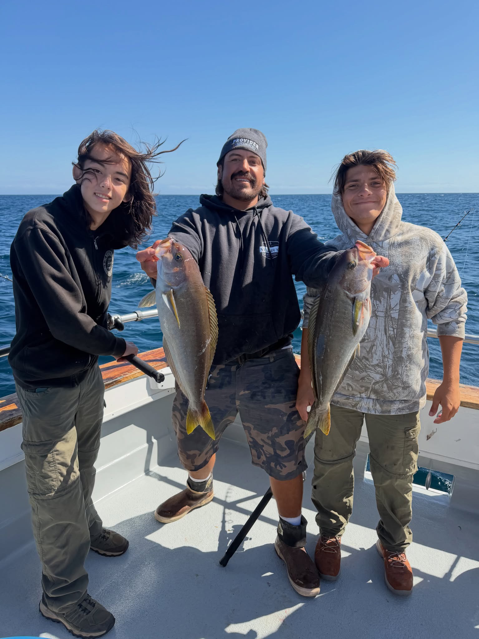 Three people fishing on boat holding catch