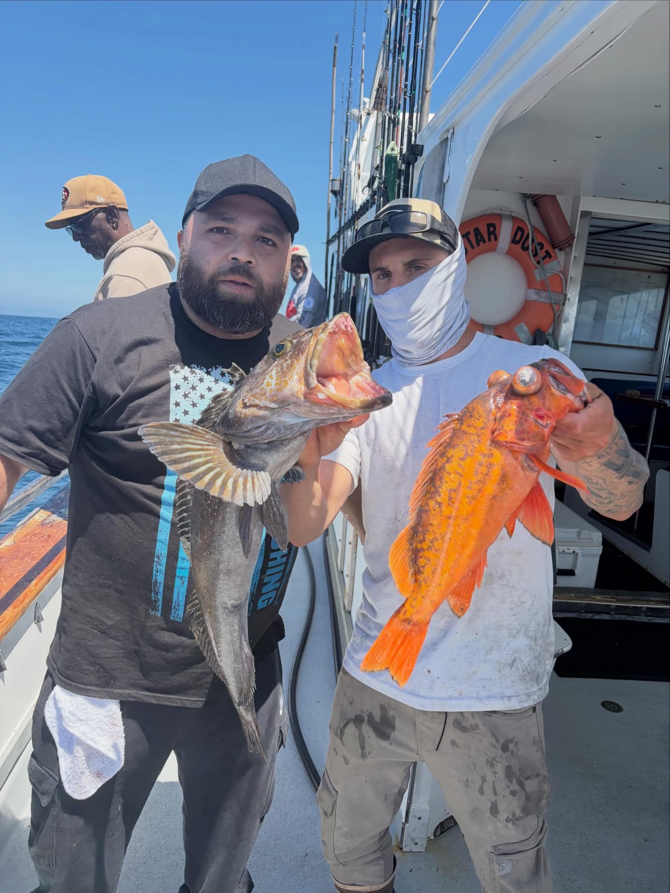 Two people holding fish on a fishing boat