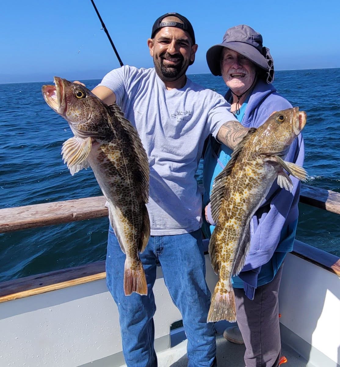 Two people holding large fish on boat