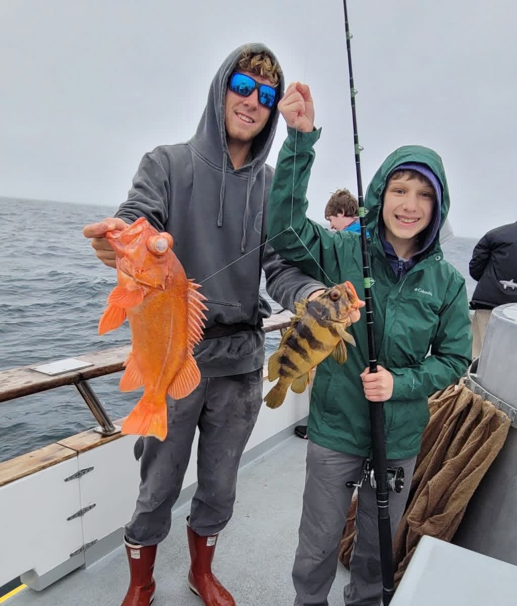 Two anglers on ocean boat holding caught fish