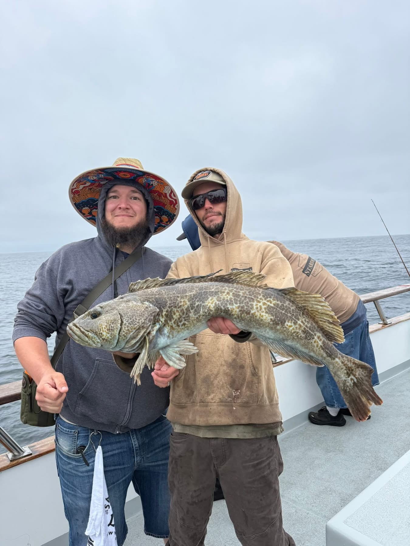 Two fishermen holding large fish on boat