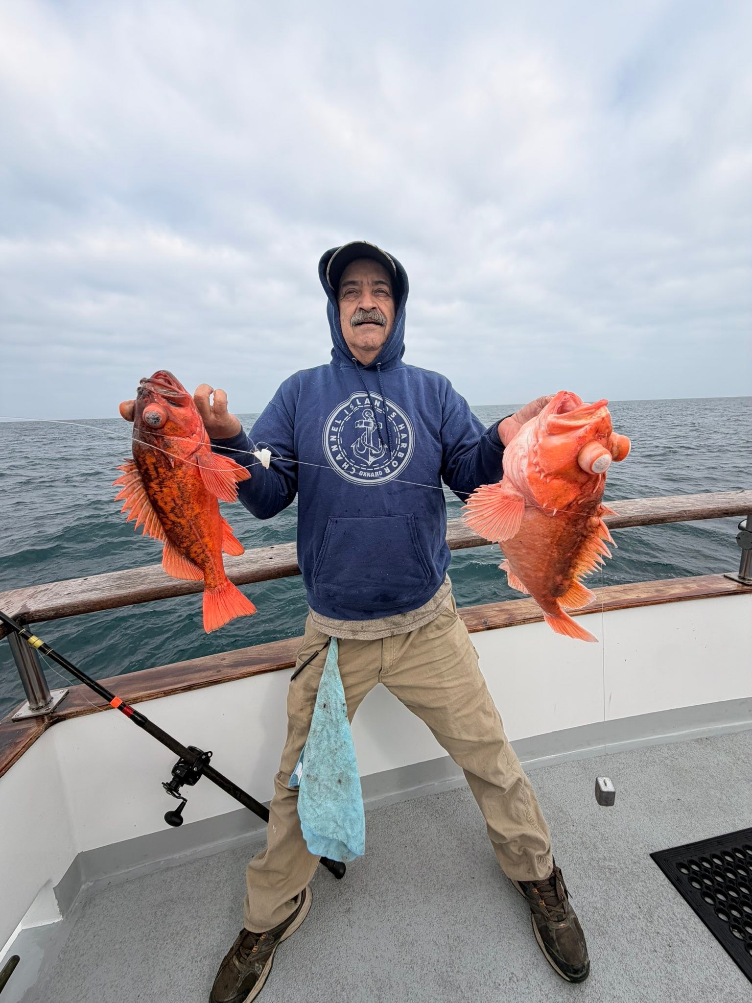 Fisherman on boat holding two large orange fish