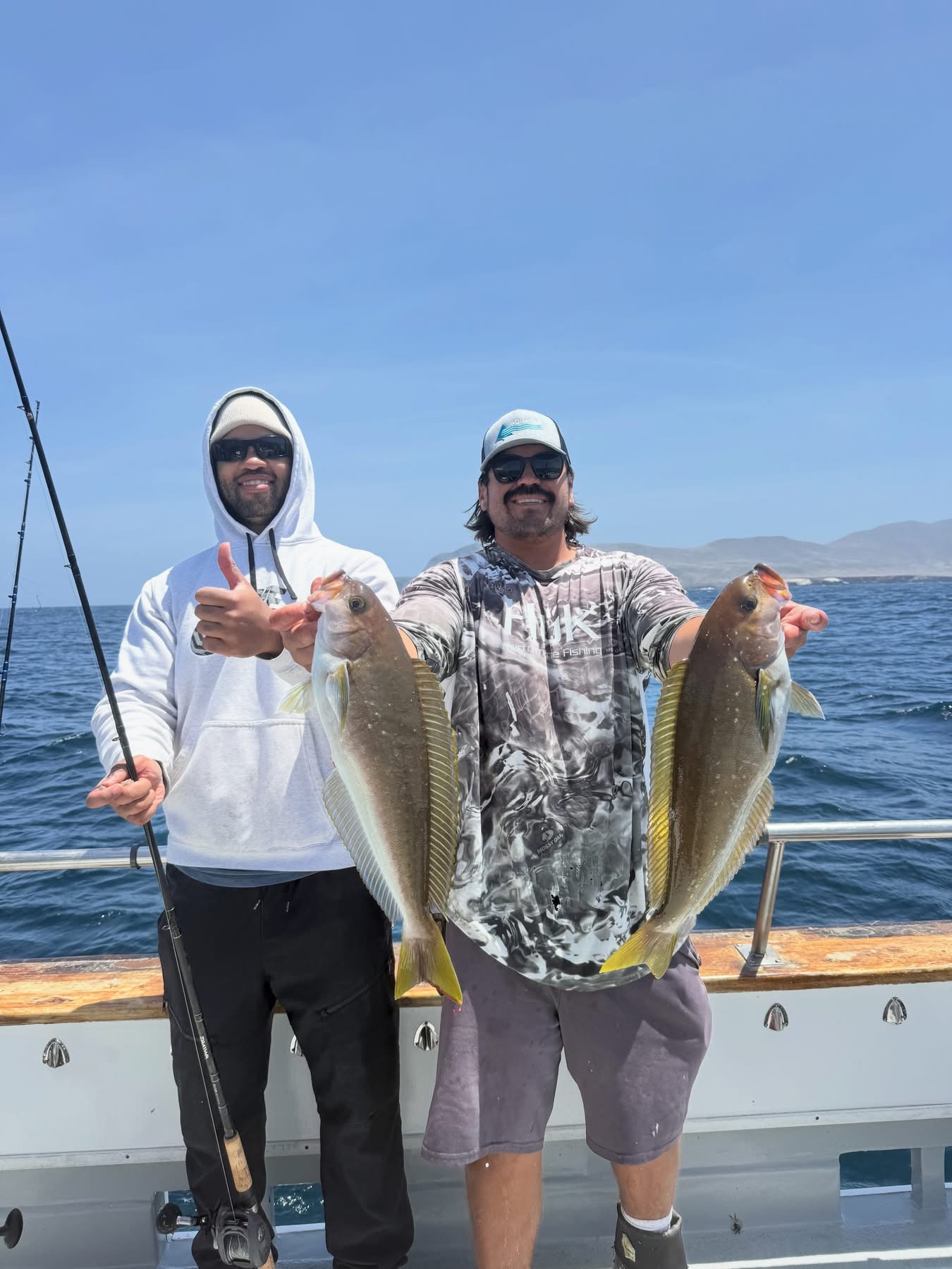 Two men on boat holding freshly caught fish