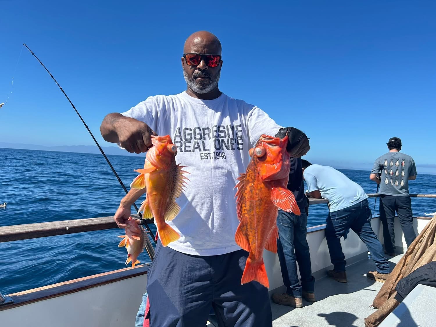Man on boat holding two orange fish