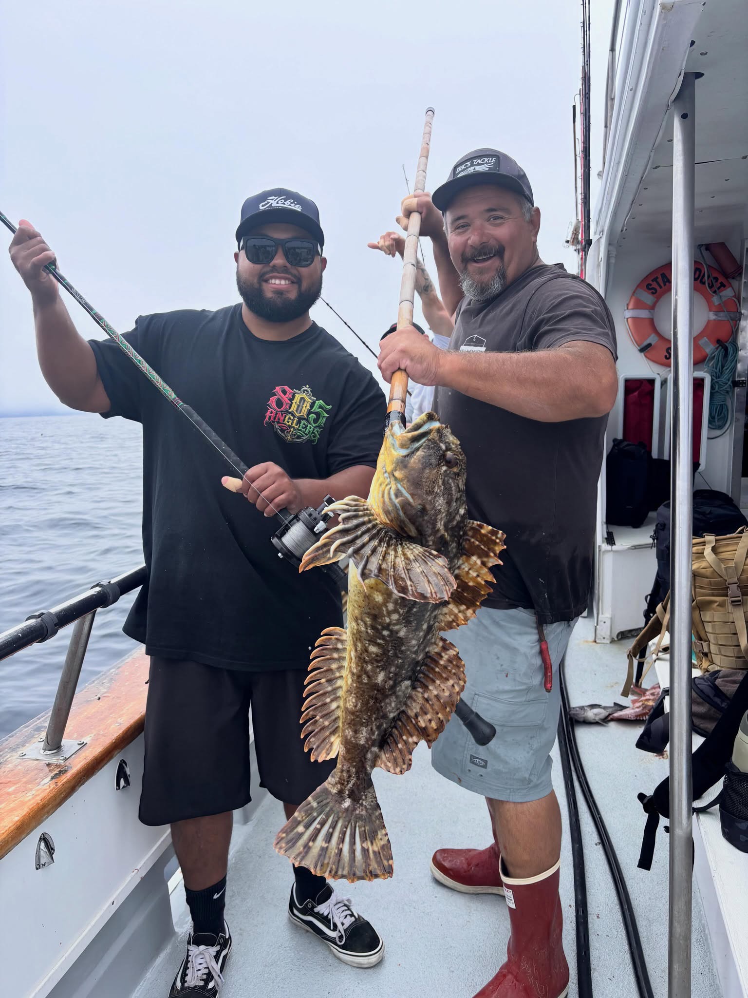 Two men on boat holding large fish