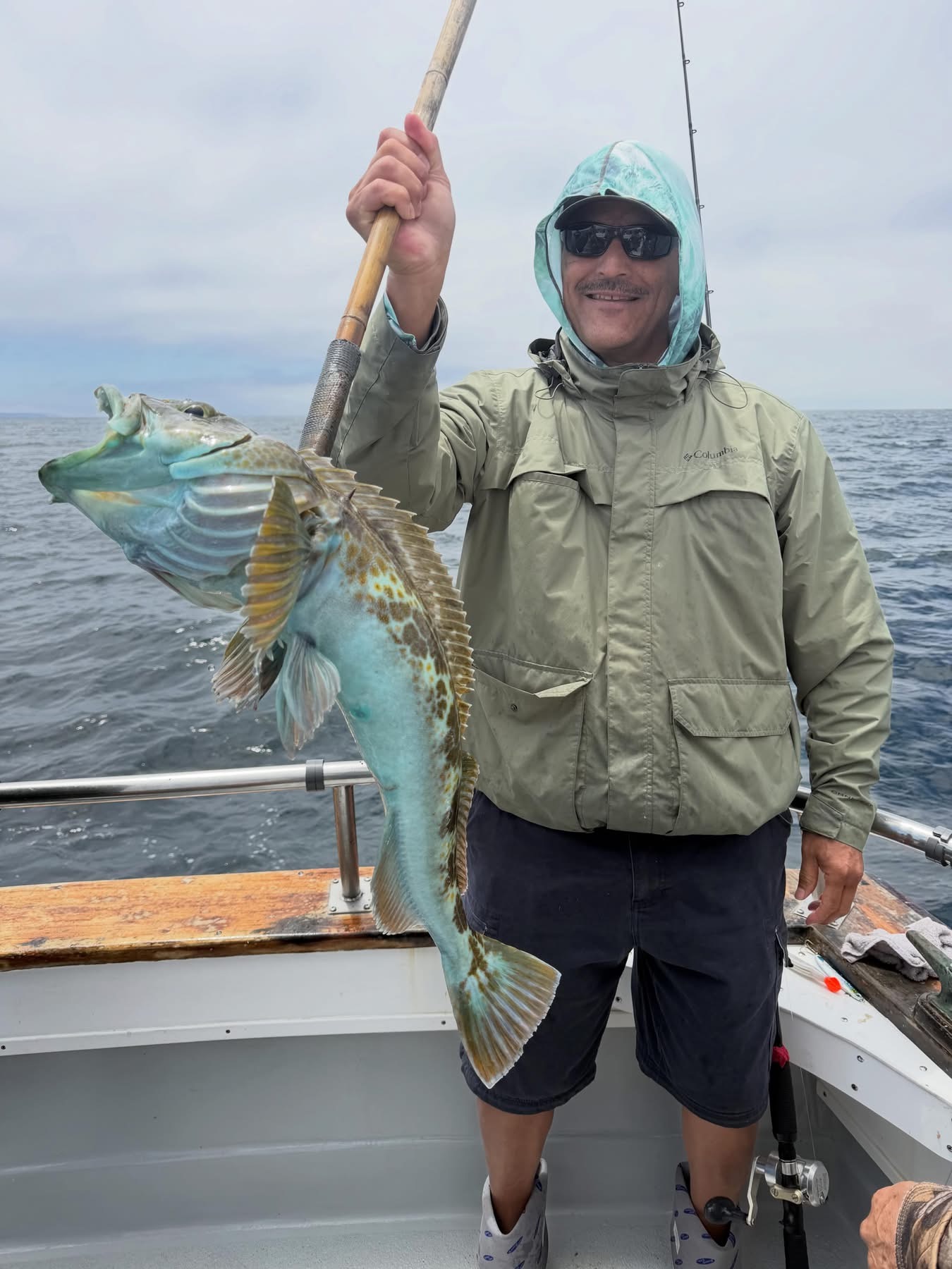 Fisherman holding large colorful fish on boat