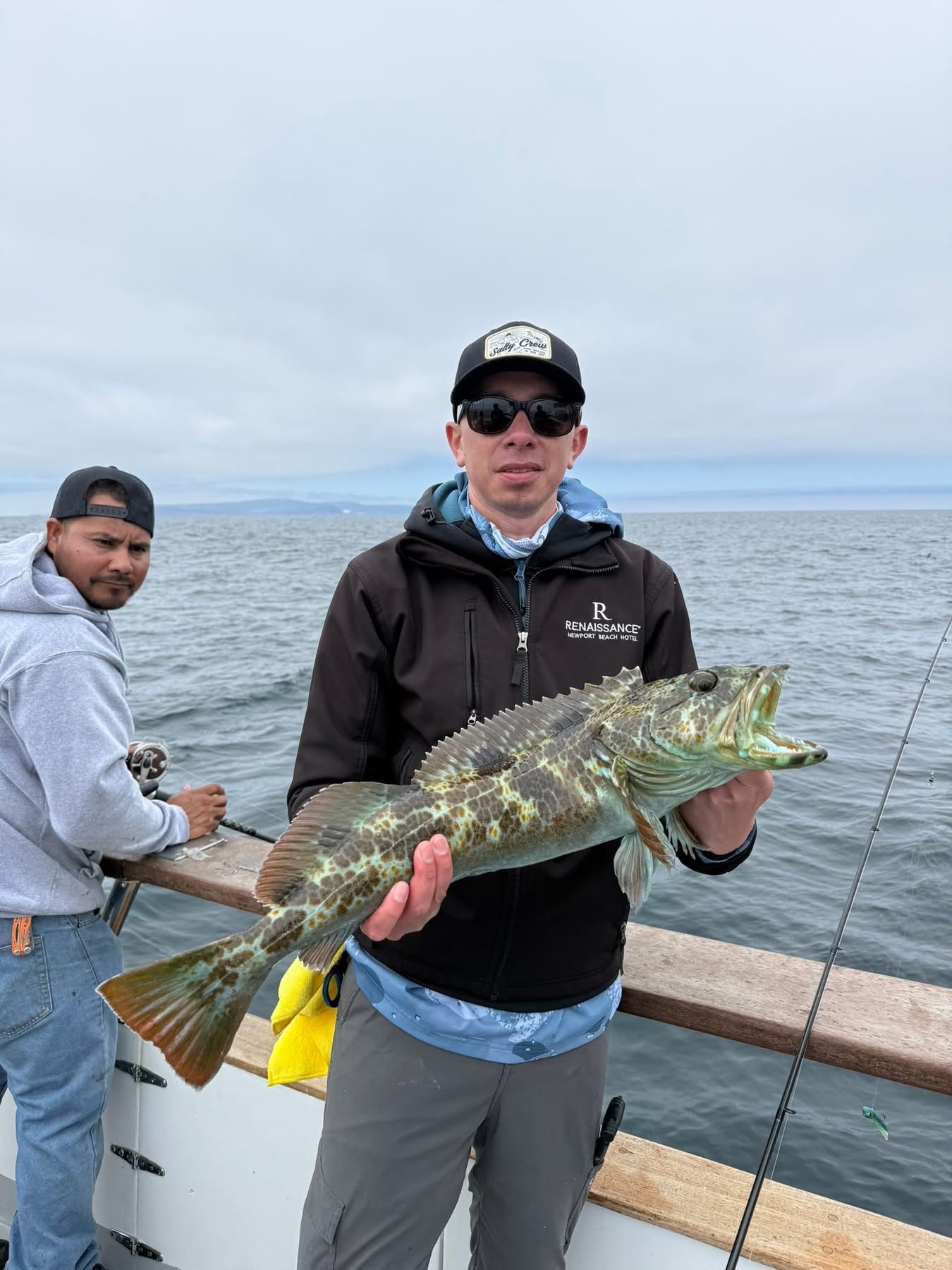 Man holding large spotted fish on boat