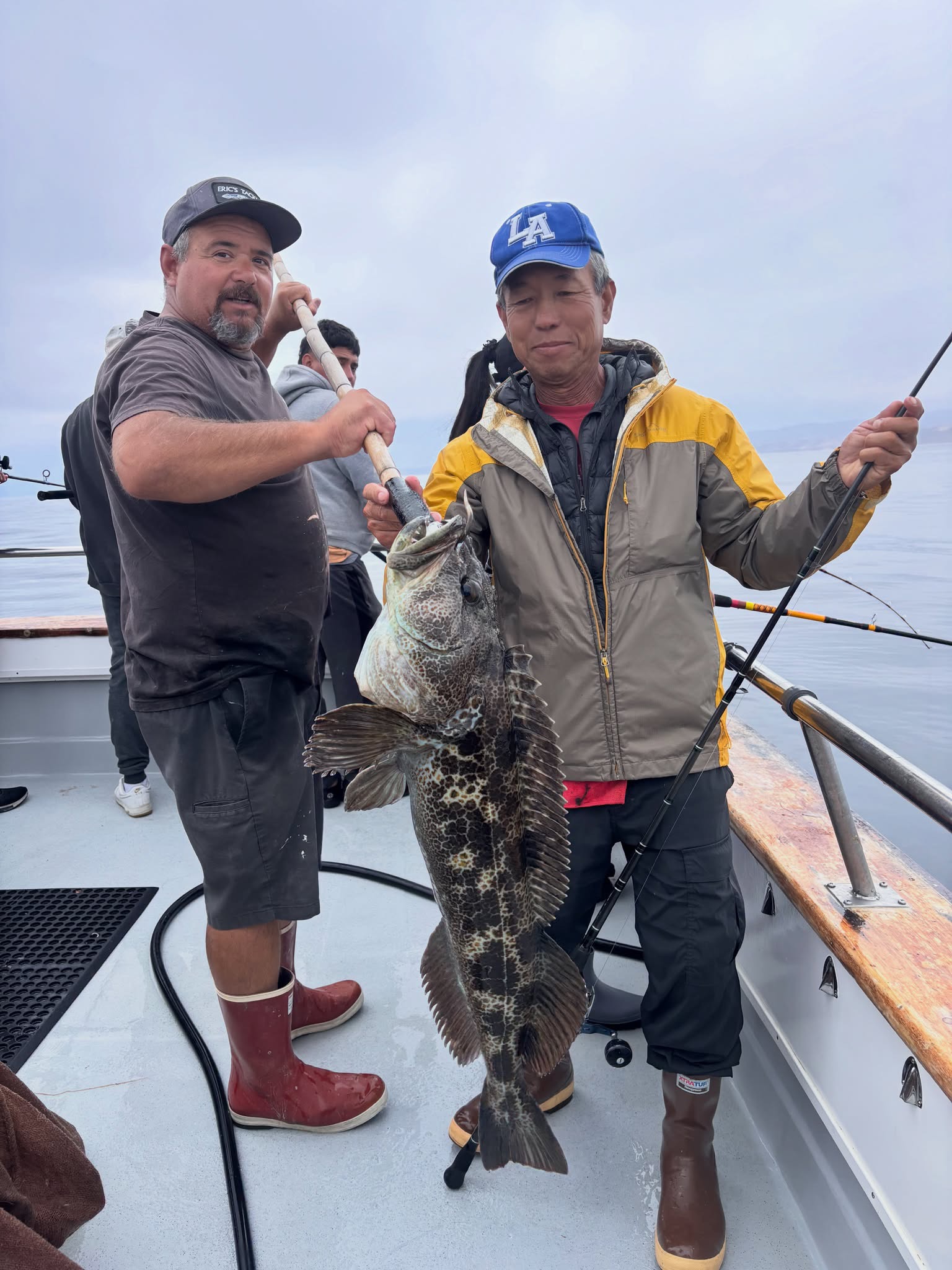 Two men holding a large fish on boat